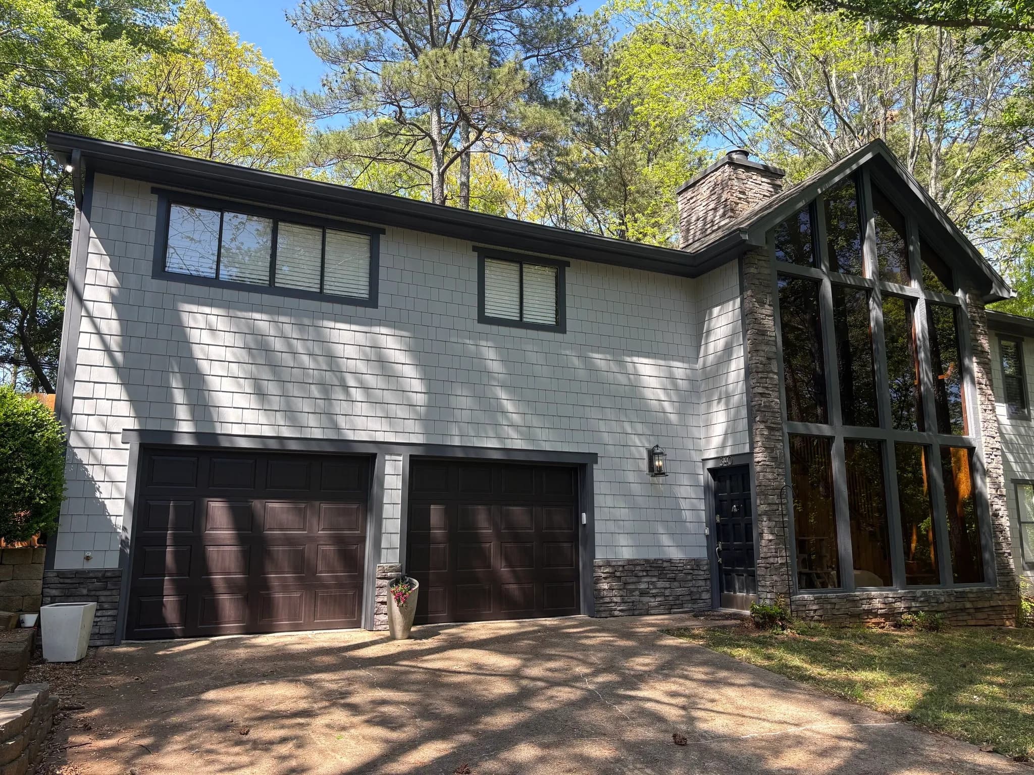 Shingle siding and exterior trim beneath mature tree cover